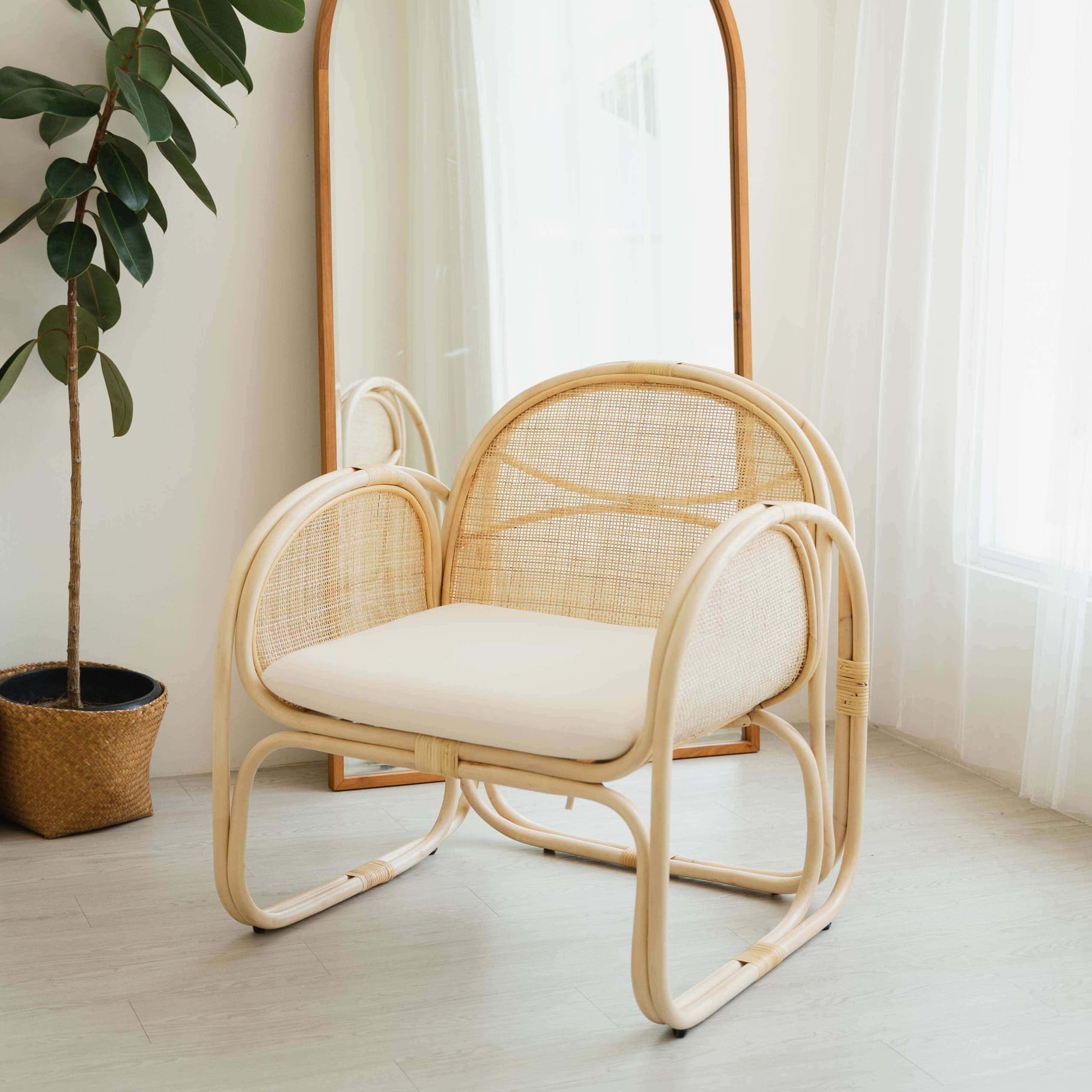 Handcrafted rattan Willow Lounge Chair by MOMIJI styled in a cozy living room with a plant and mirror.