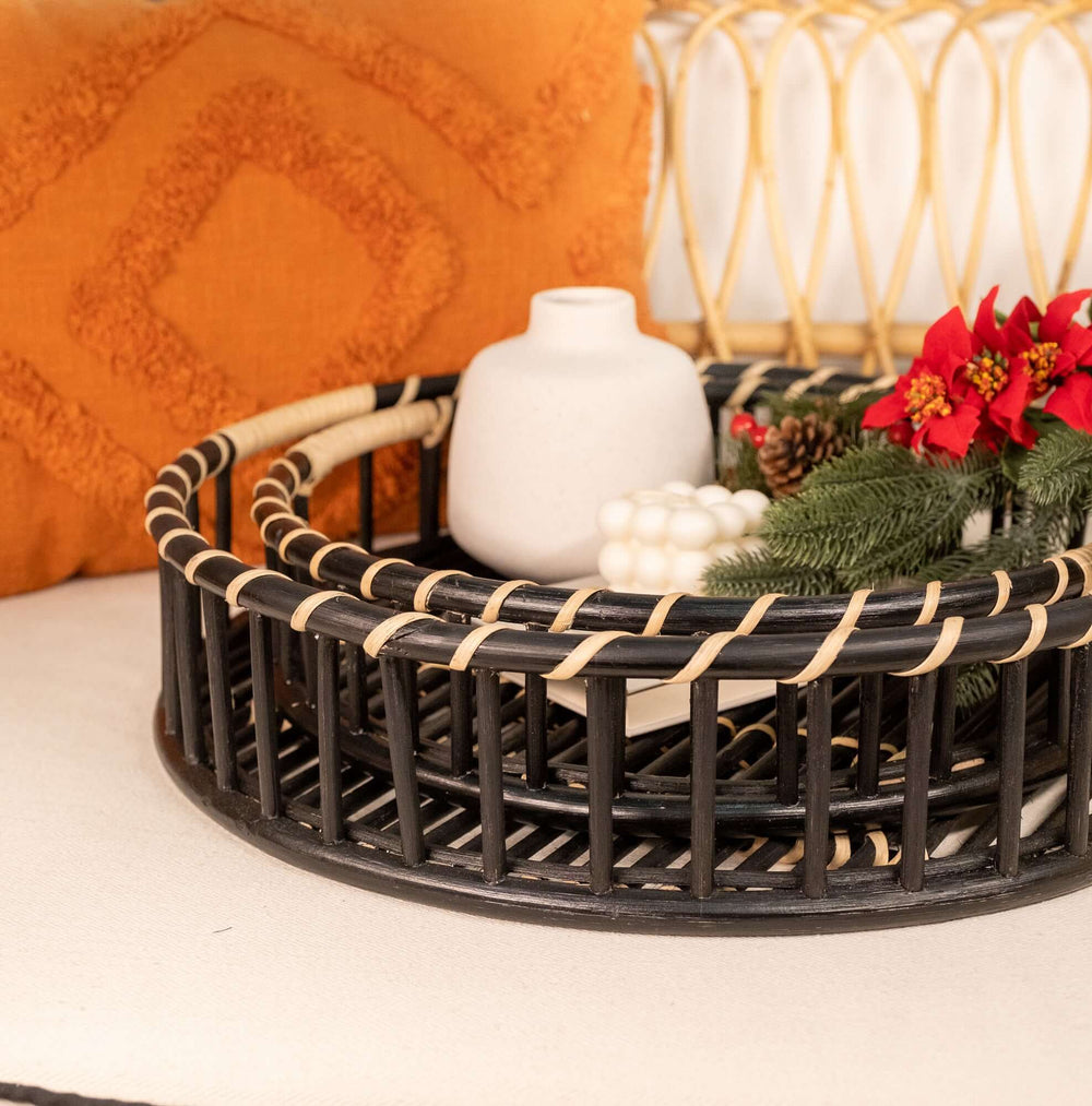Handcrafted Maru Tray Set by MOMIJI in balck and natural stripe rattan with a white vase and festive decorations on a textured surface.