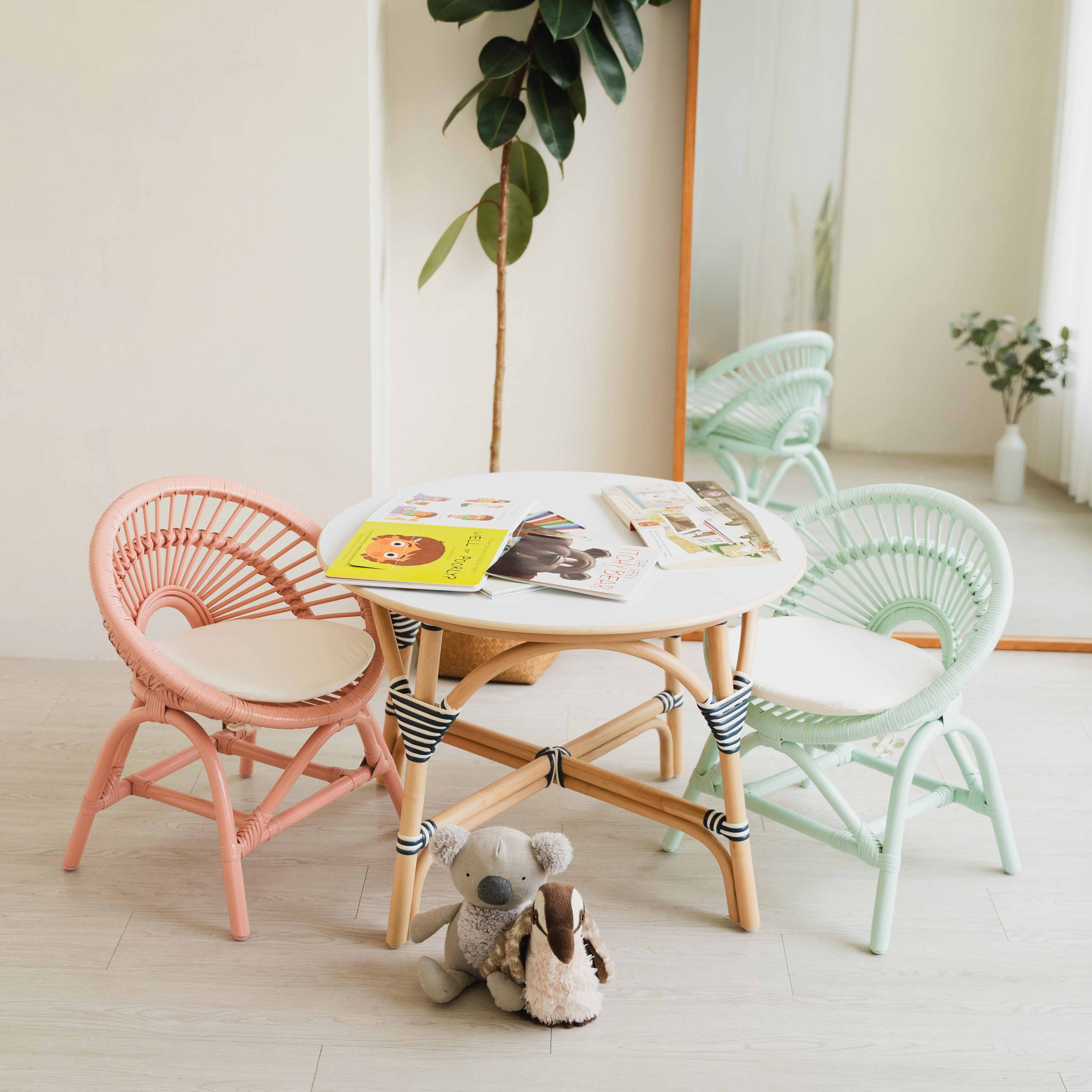 Handcrafted Peach Pink and Mint Green rattan Maya Kids Chairs by MOMIJI styled with an Aulia Kids Table, a mirror, and toys in a playful children's room.