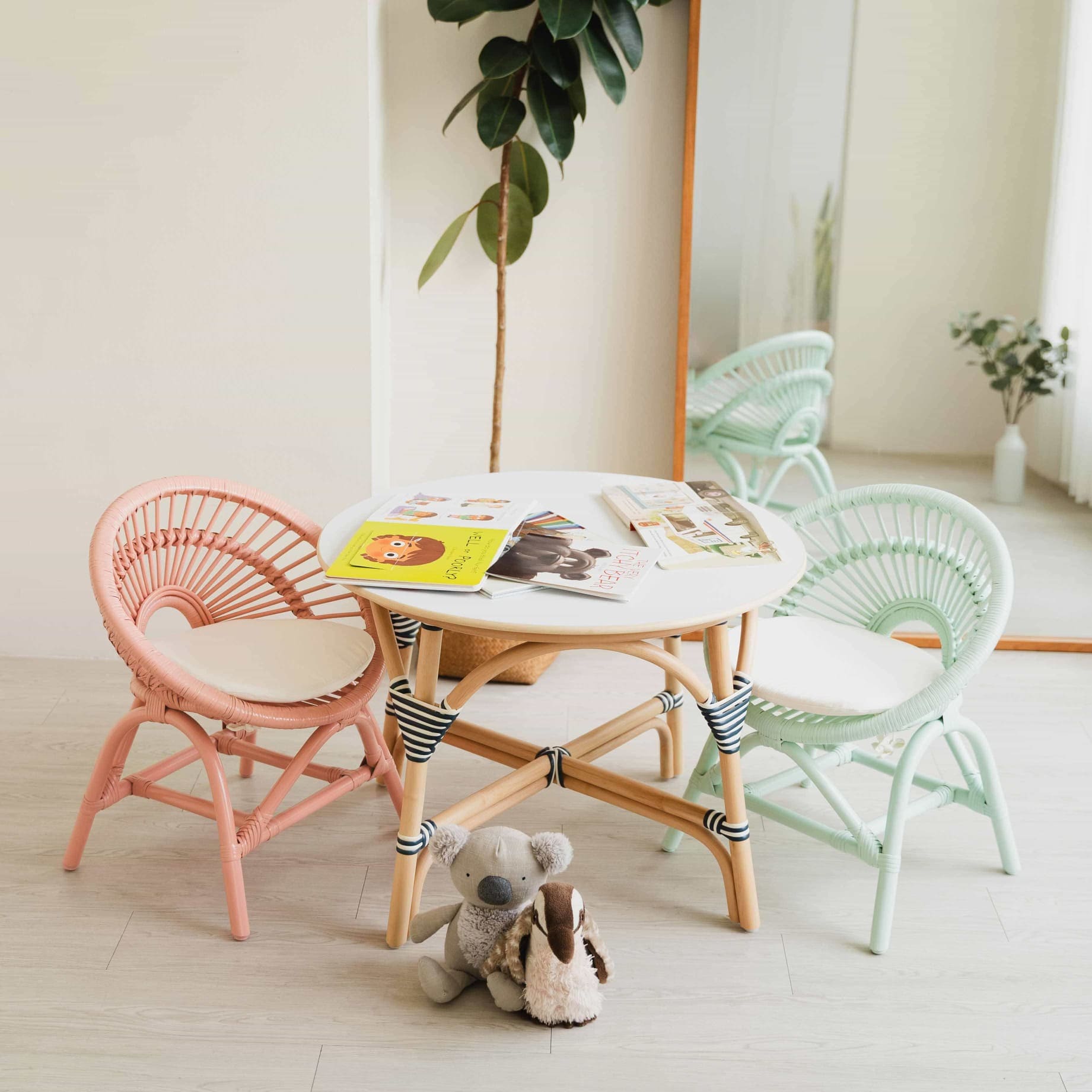 Maya Kids Chair peach pink and mint green by MOMIJI styled with a rattan table, mirror, and toys in a room.