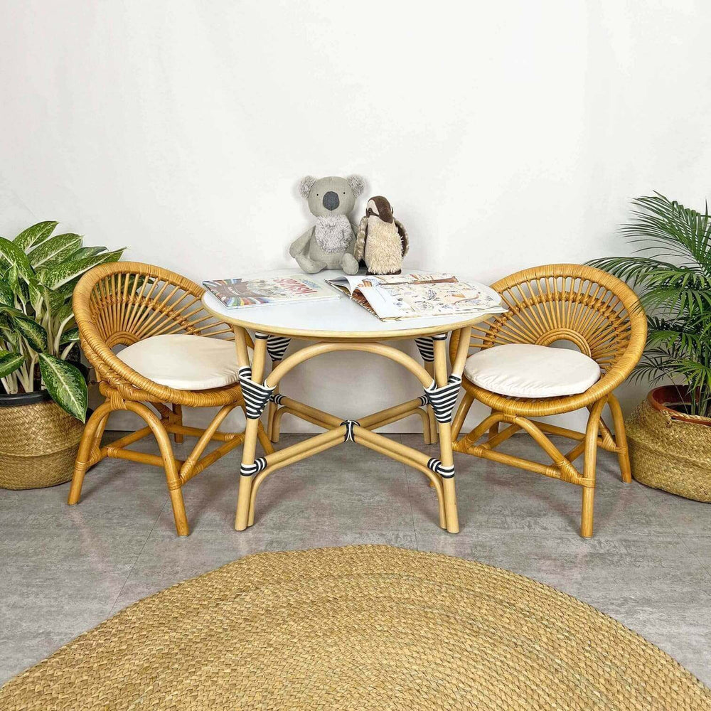 Maya Kids Chair by MOMIJI styled with a matching table and a doll in a room with plants.