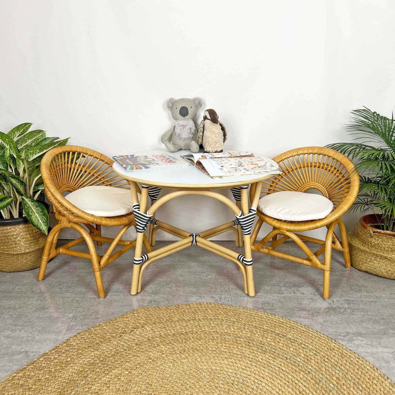 Maya Kids Chair by MOMIJI styled with a matching table and a doll in a room with plants.