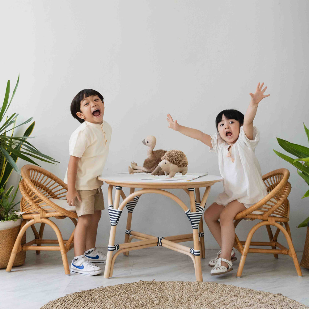 Two children enjoying playtime with the Maya Kids Chair and table by MOMIJI in a room.