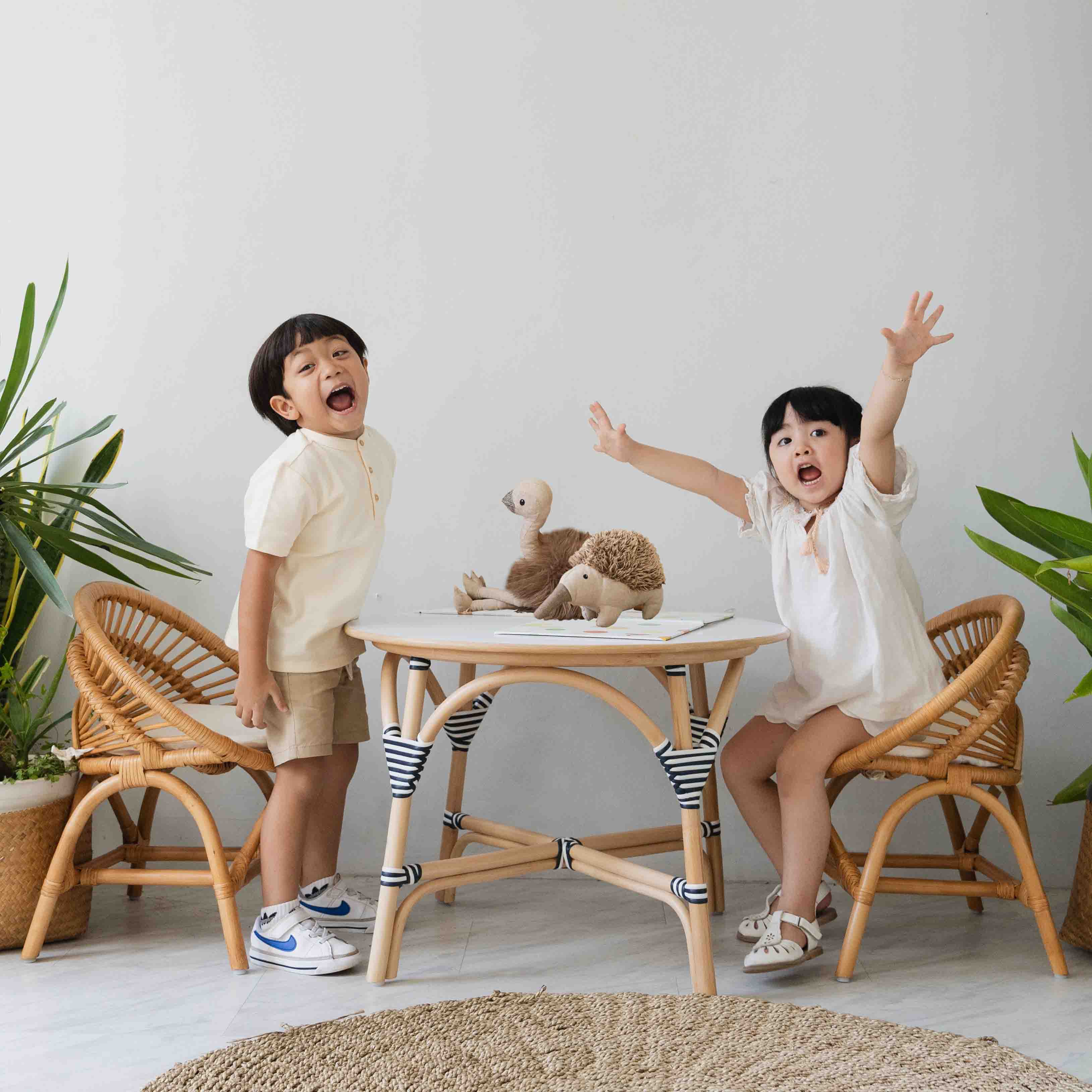 Two children enjoying playtime with the Maya Kids Chair and table by MOMIJI in a room.