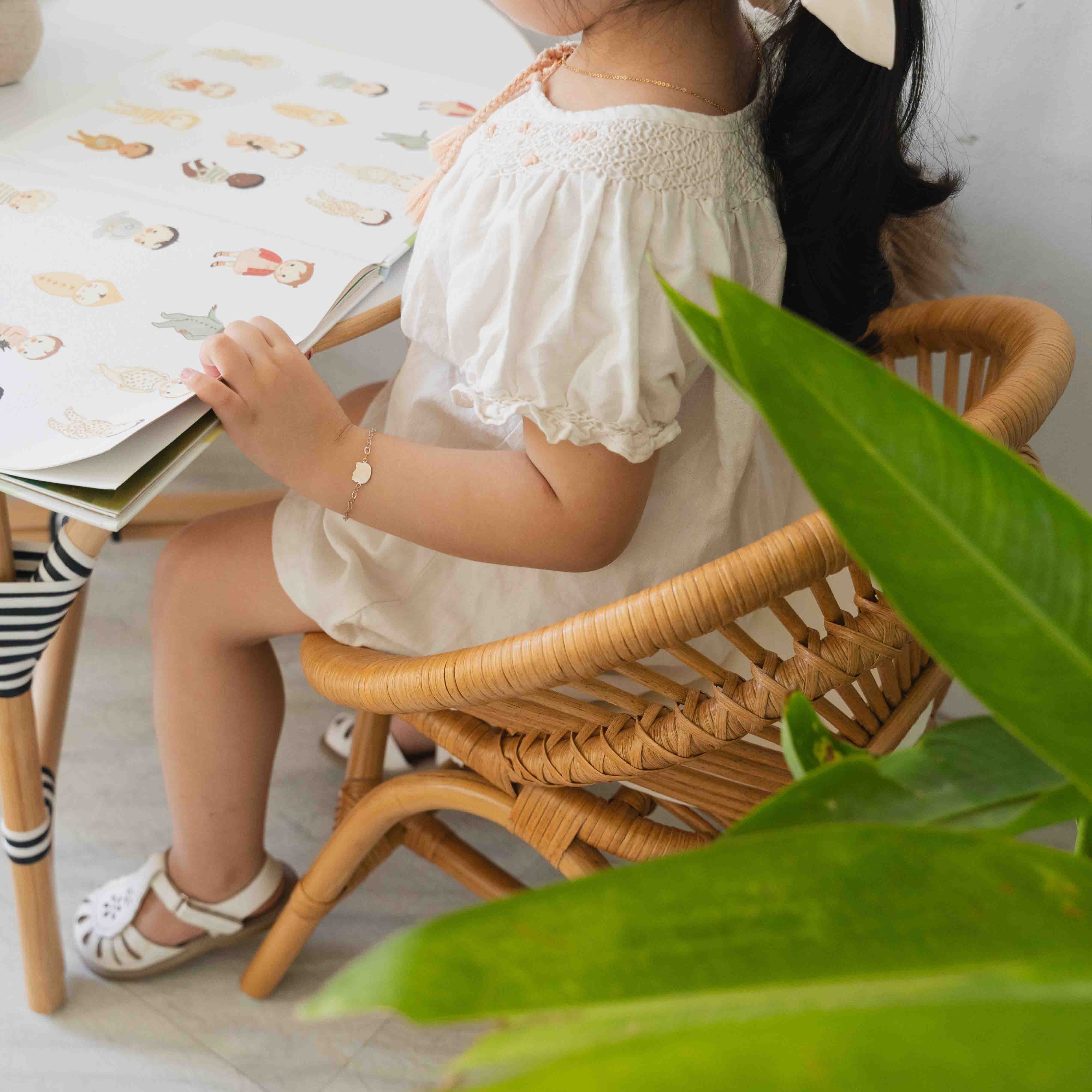 Close-up of a child sitting on the Maya Kids Chair by MOMIJI while reading a book at a table.