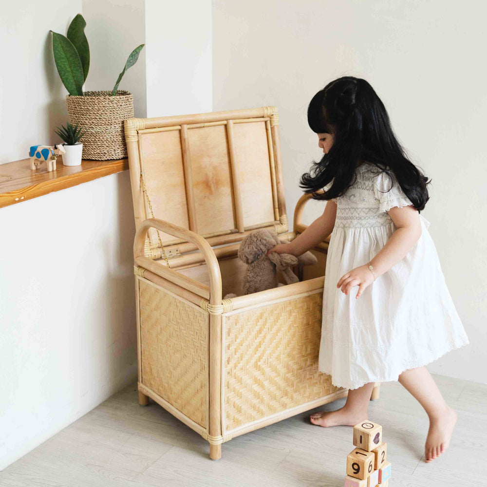Child placing toys into the Mia Storage Bench by MOMIJI in an indoor setting.