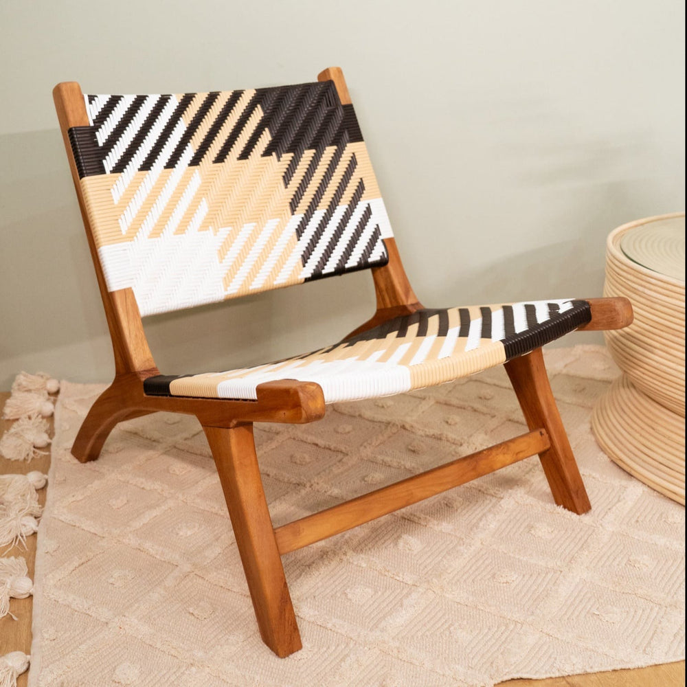 Angled view of the Mila Plaid Lounge Chair by MOMIJI placed on a white rug beside a coffee table.