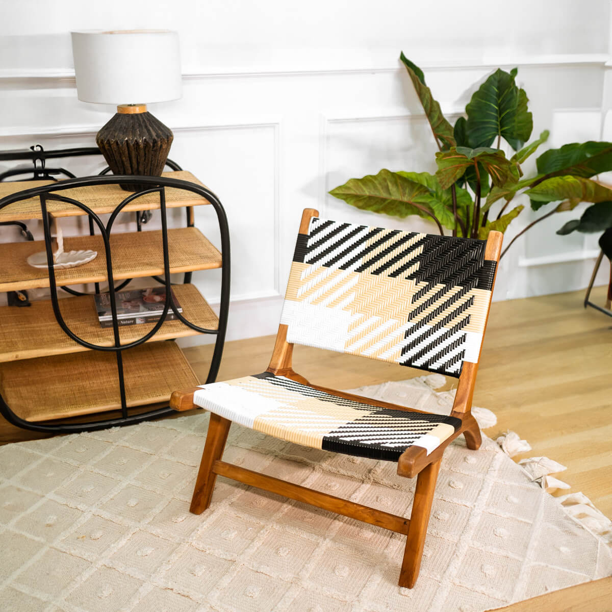 Mila Plaid Lounge Chair by MOMIJI placed on a rug in a room with a bar cart and indoor plants.