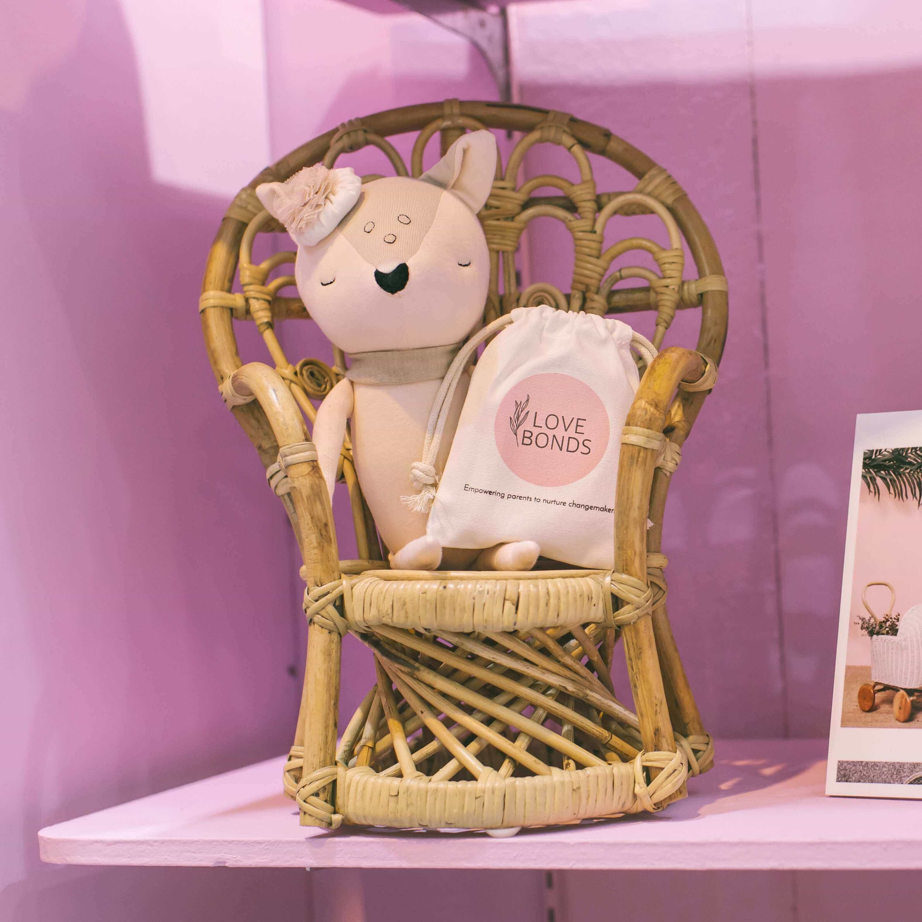 Doll seated on the handcrafted rattan wicker Mini Peacock Doll Chair by MOMIJI styled on a shelf corner.