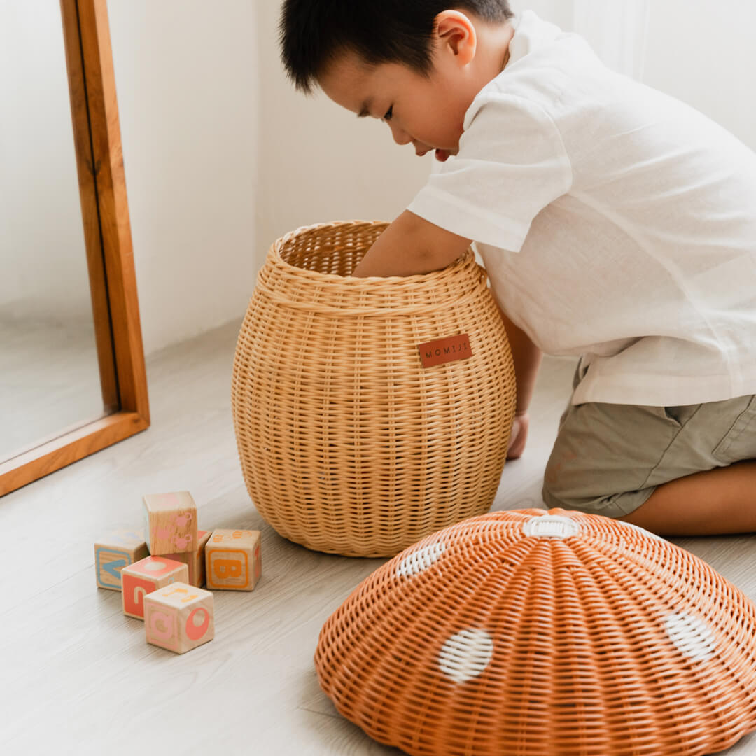 Child putting his hand inside the Mushroom Storage Rattan Basket by MOMIJI.