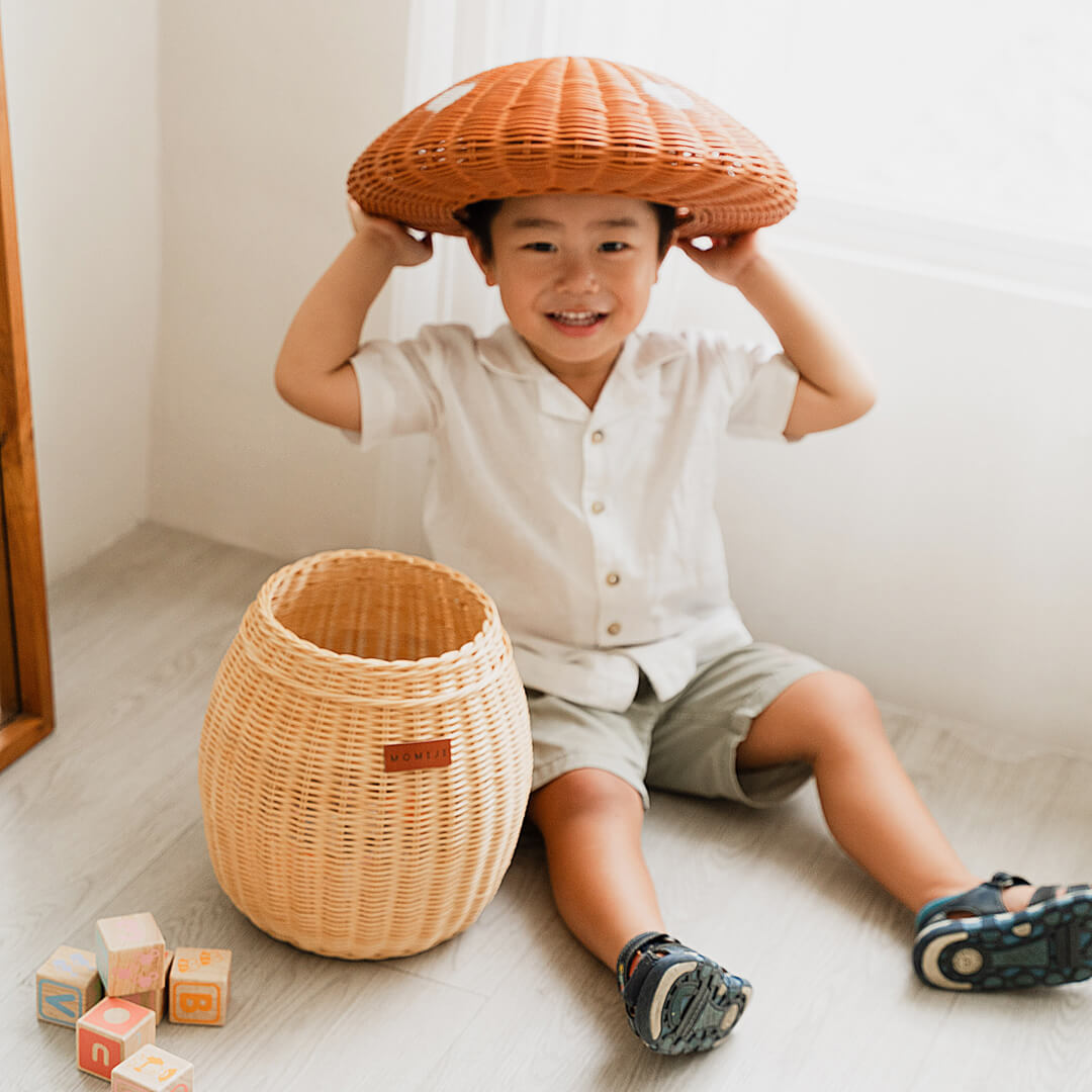 Child putting the Mushroom Storage Rattan Basket lid on his head.