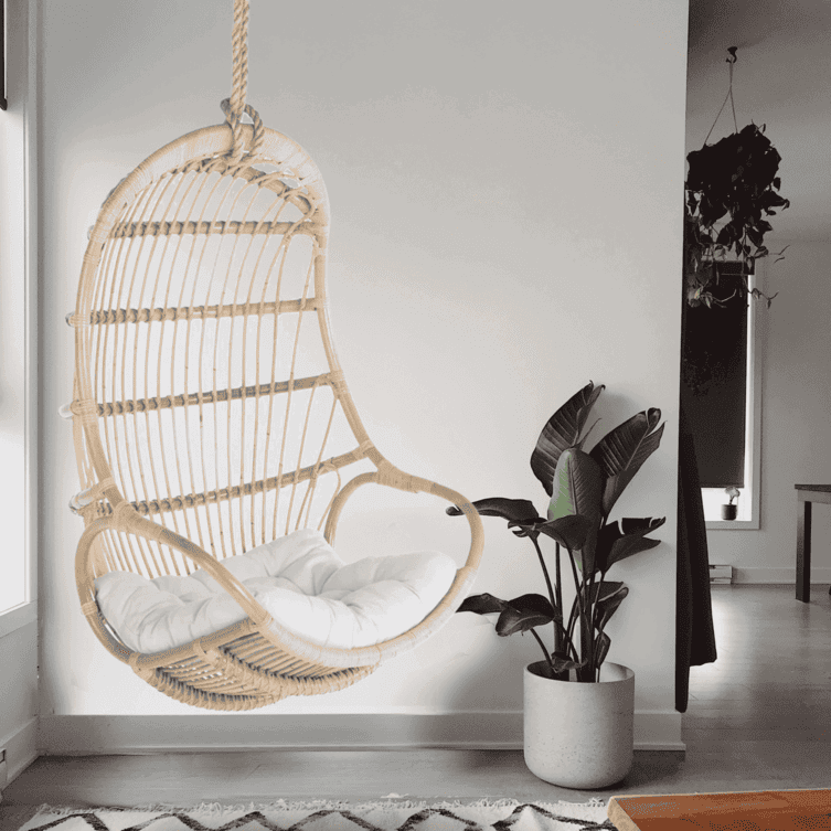 Woven Nest Hanging Chair by MOMIJI with a white cushion, styled in a room with a rug and plants.