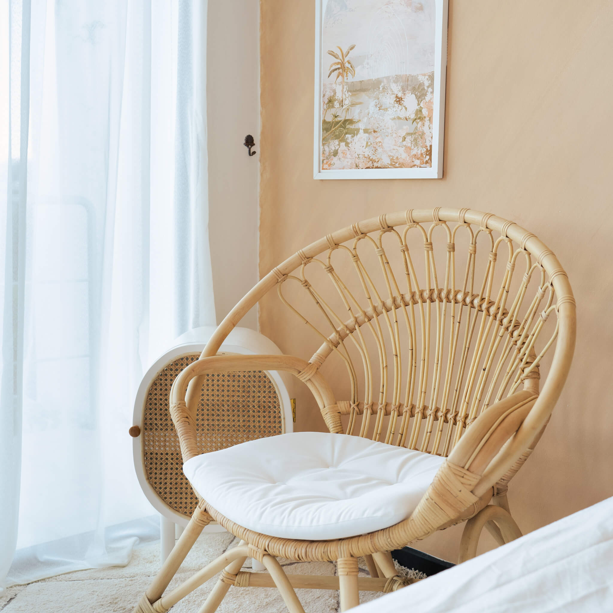 Nest Lounge Chair by MOMIJI with a white cushion, positioned in a room with curtains and wall art.