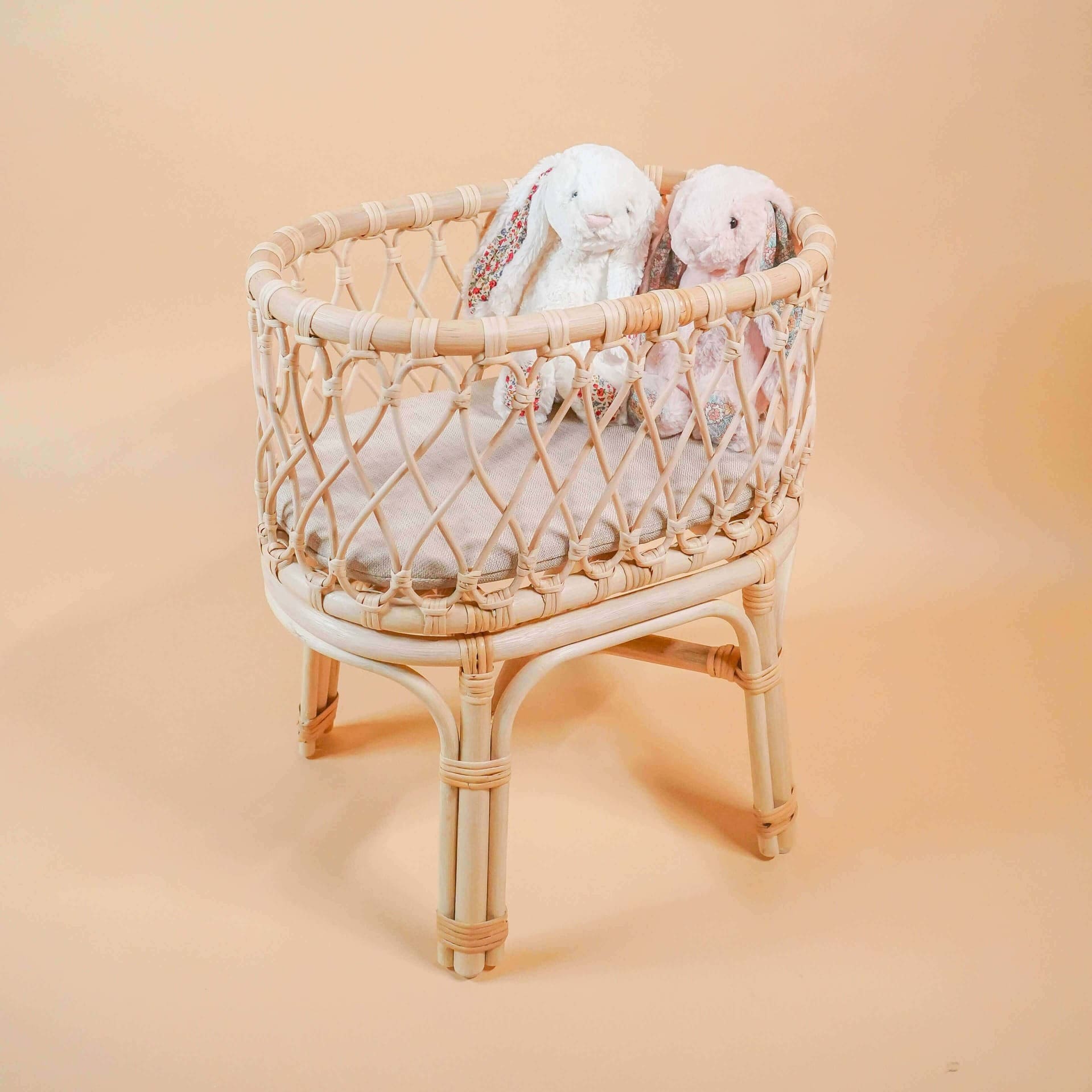 Angled view of the Olivia Doll Bassinet by MOMIJI with a bunny doll inside.