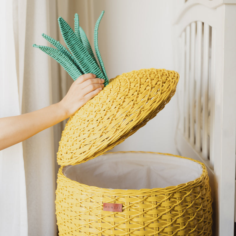 Hand opening a yellow Pineapple Rattan Storage Basket by MOMIJI.