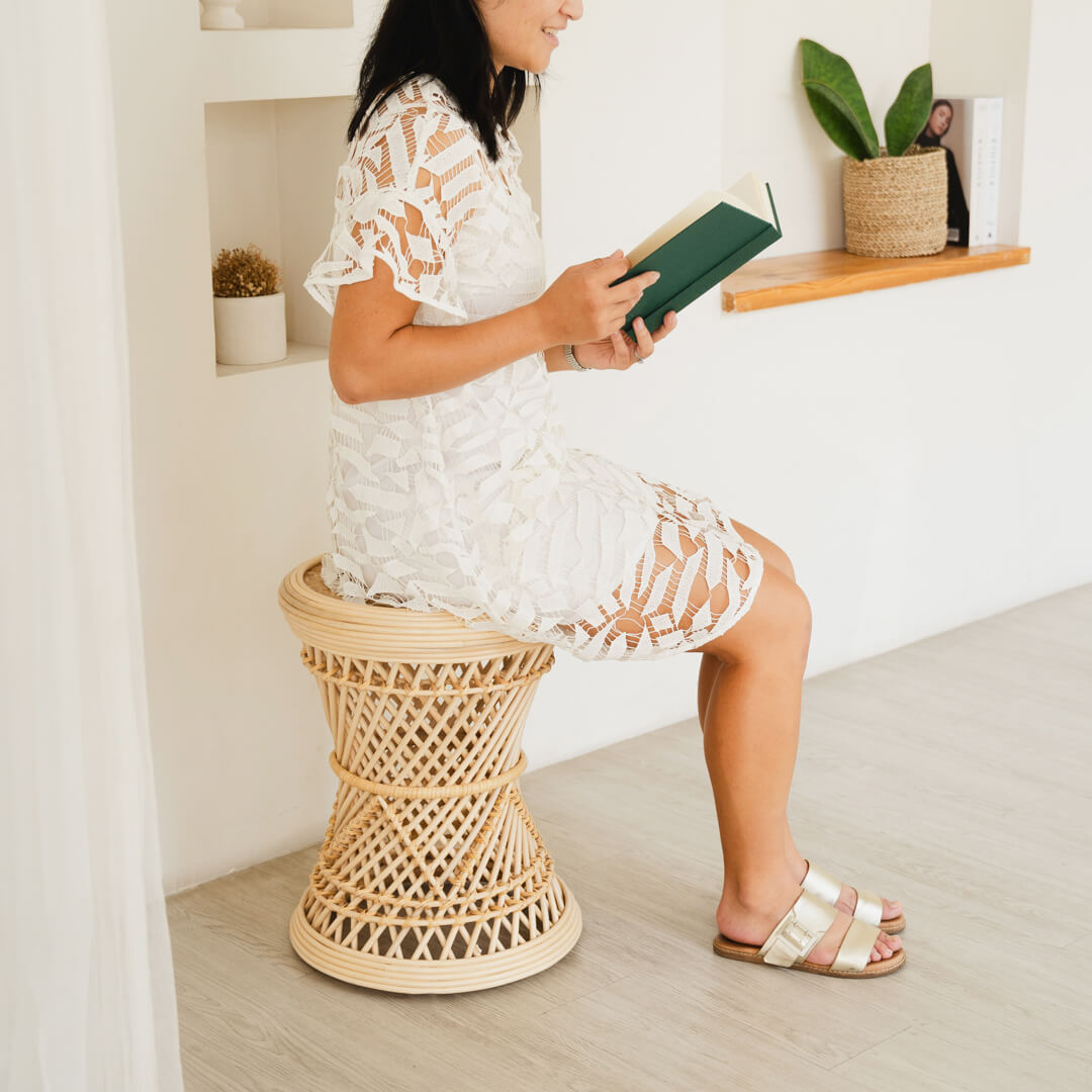 Woman sitting on the Palawan Stool by MOMIJI while reading a book in a styled interior.