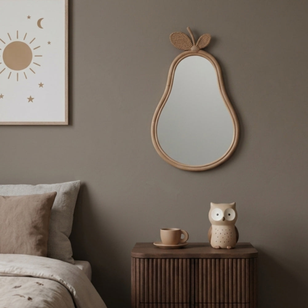 Handcrafted rattan wicker Pear Mirror by MOMIJI displayed on a neutral bedroom wall above a wooden bedside table with minimalist décor.