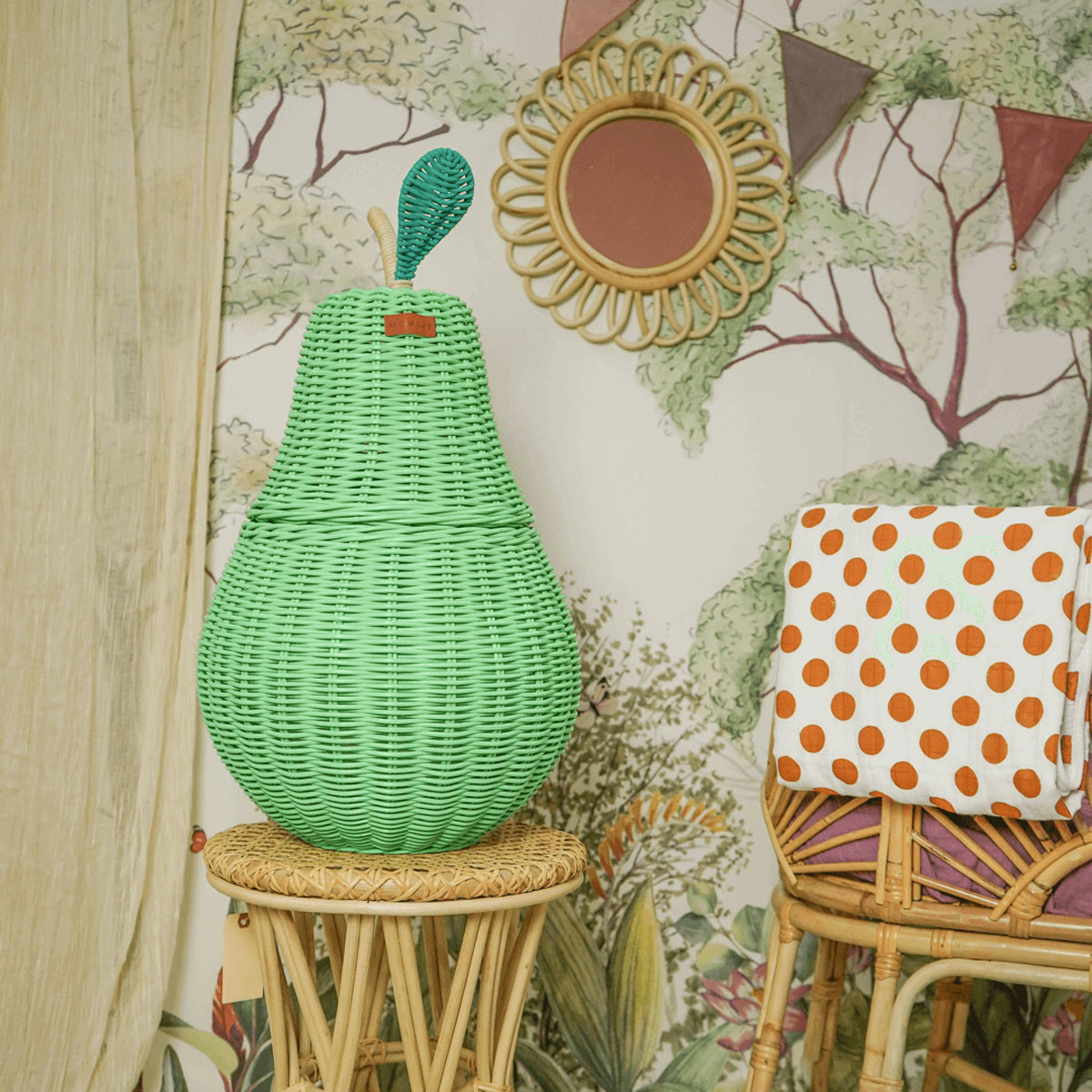 Pear Rattan Storage Basket by MOMIJI on top of a rattan stool.