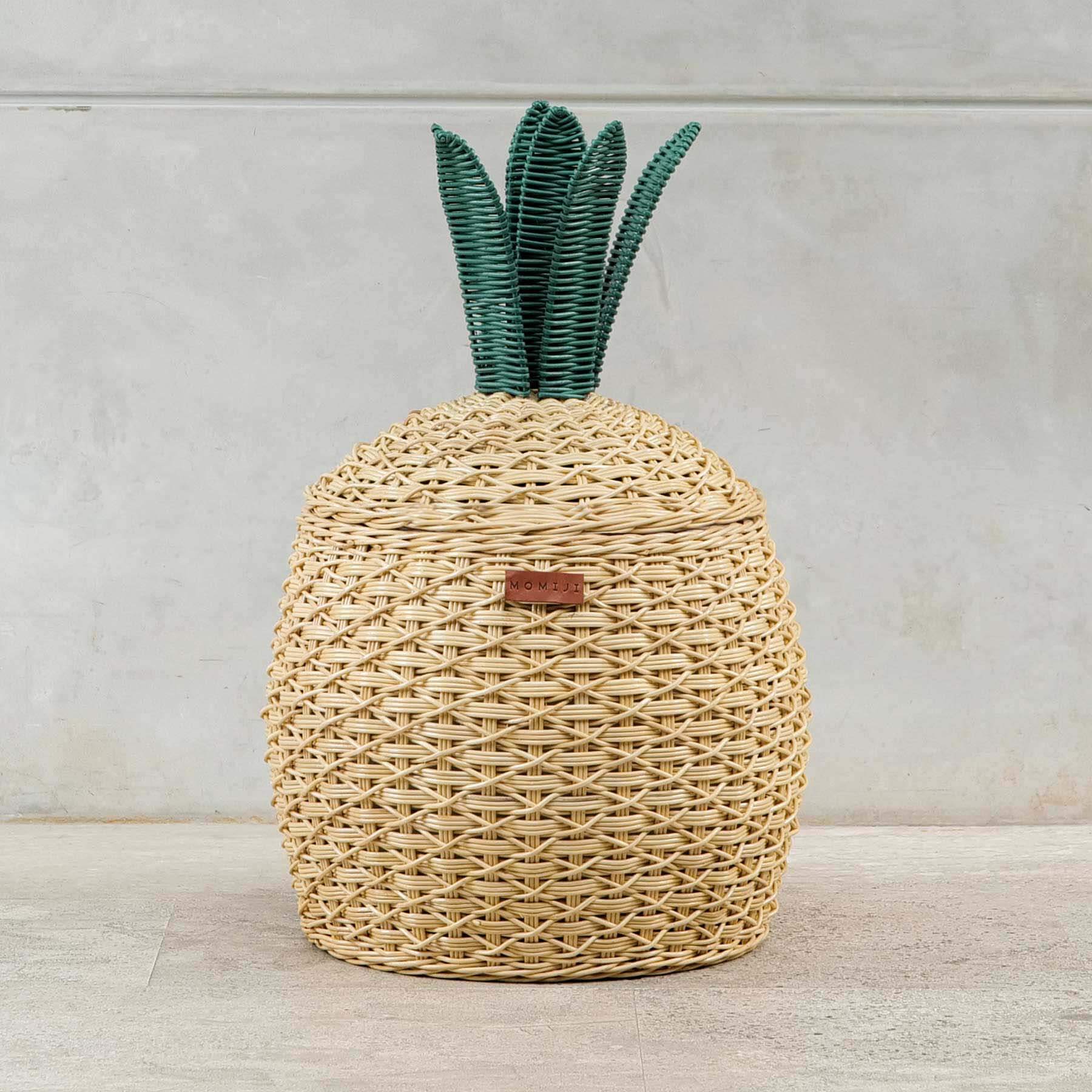 Front view shot of Pineapple Rattan Storage Basket by MOMIJI on a light wooden floor.