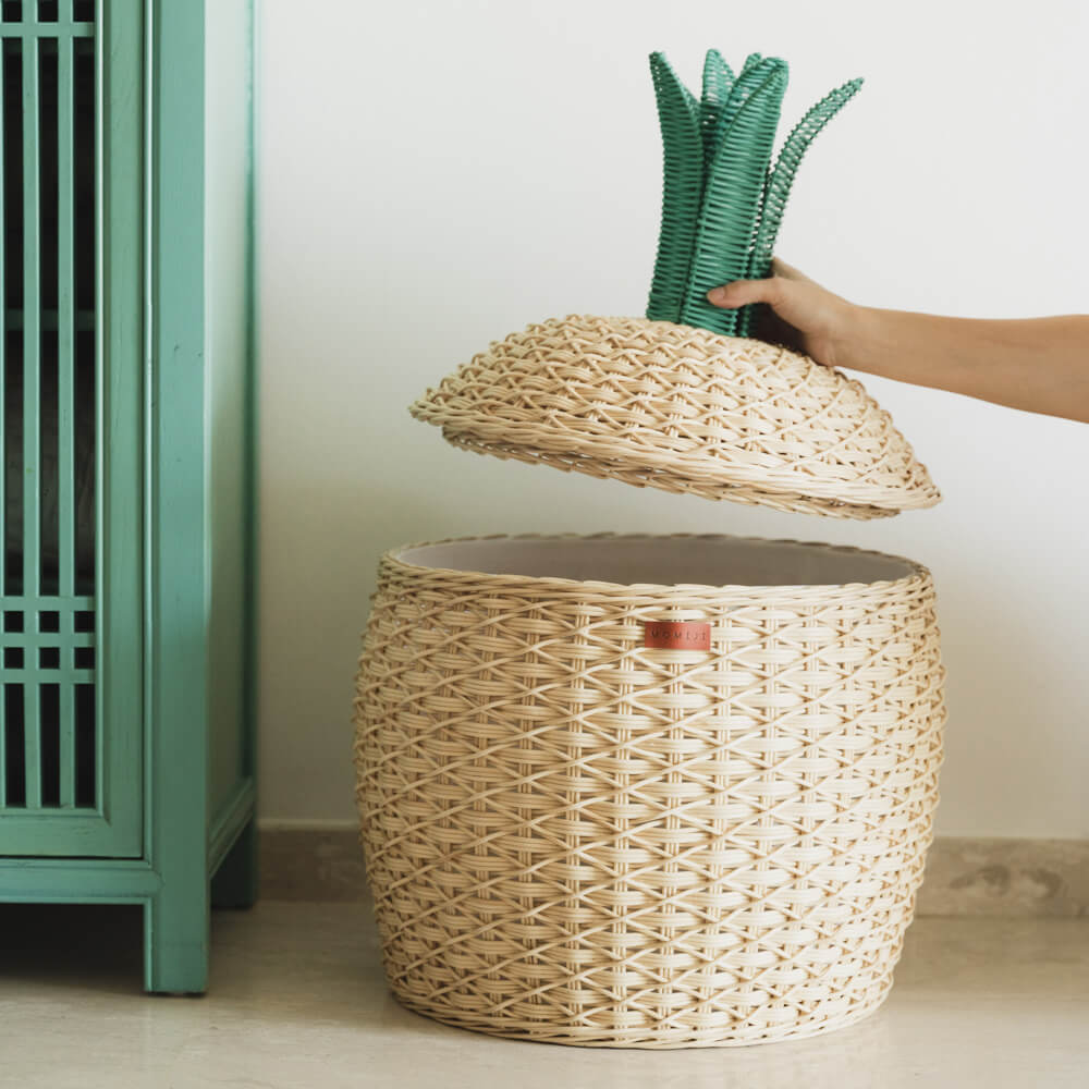 Hand holing the lid of the Pineapple Rattan Storage Basket by MOMIJI, opening the rattan basket.