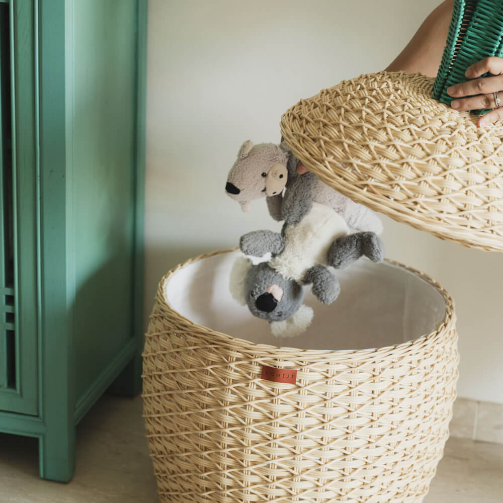 a hand, putting toys inside the Pineapple Rattan Storage Basket by MOMIJI.