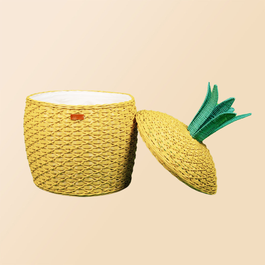 Front view of an opened yellow Pineapple Rattan Storage Basket with lid leaning beside the basket.