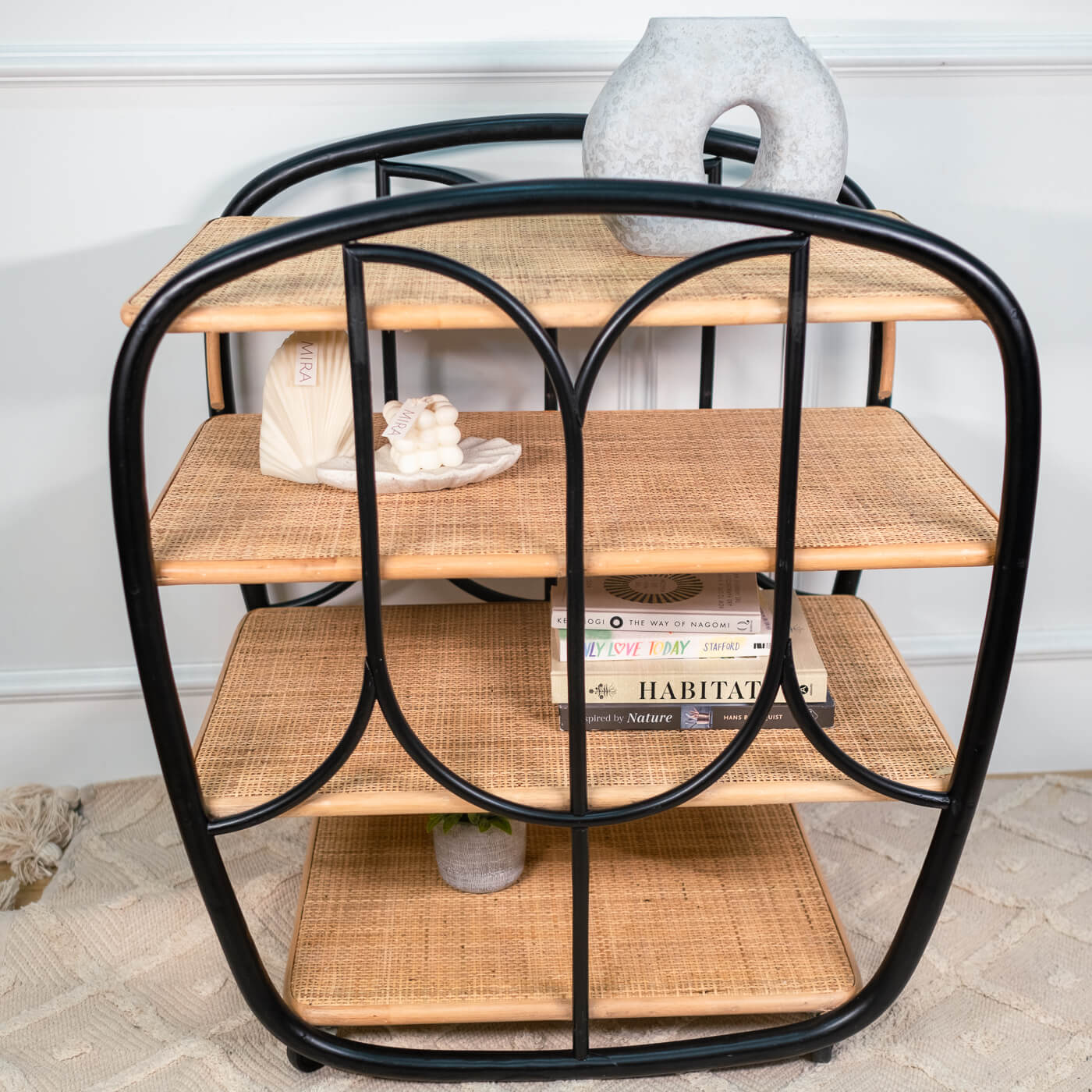Front view of the handcrafted rattan Posy Bar Cart by MOMIJI  featuring a black frame, four woven rattan shelves, styled indoors.
