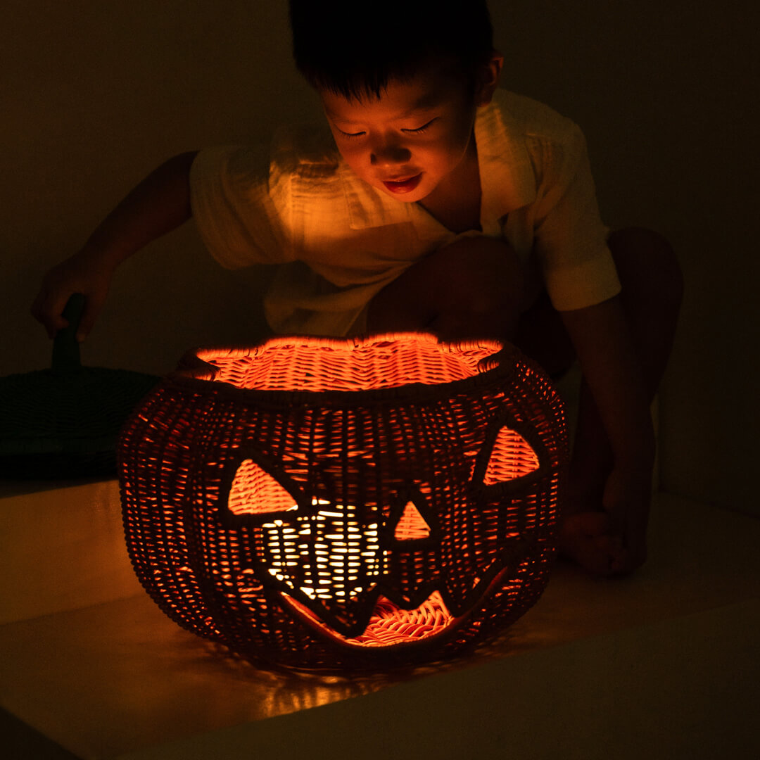 Child looking at the light inside the Pumpkin Face Rattan Basket by MOMIJI.