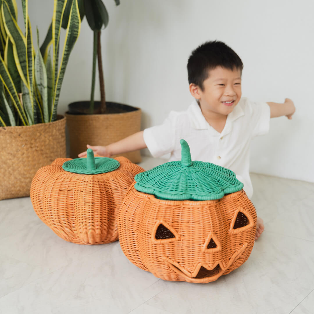 Child happily playing with the Pumpkin Face Rattan Basket by MOMIJI.