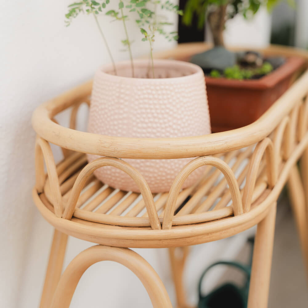 Close-up of the woven joinery detail of the Sage Wicker Plant Stand by MOMIJI with a potted plant on top.