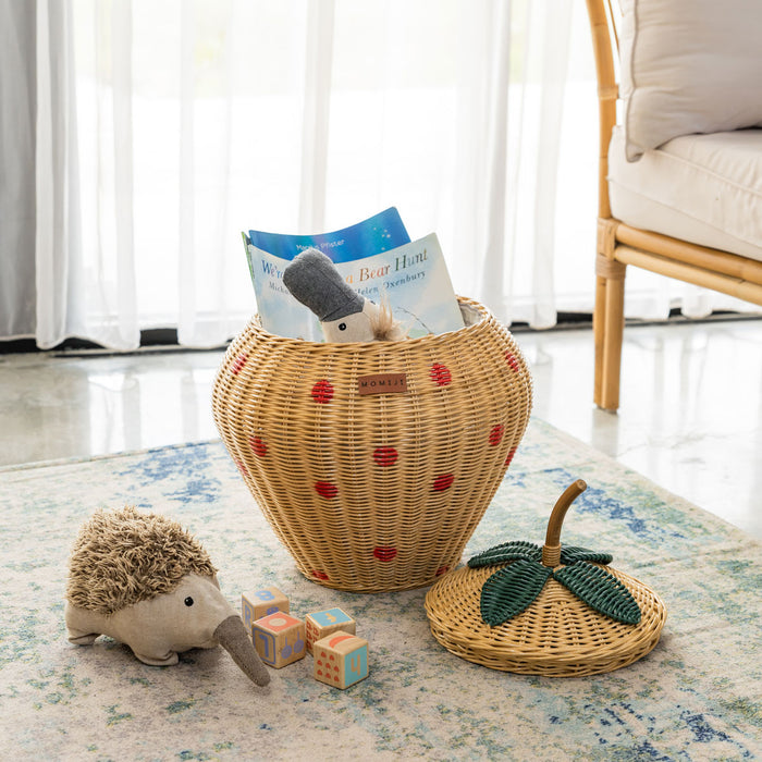 Handcrafted trawberry rattan wicker pineapple storage basket by MOMIJI, shown with the lid off and filled with toys and books on a rug, ssupporting Montessori-inspired tidy habits.