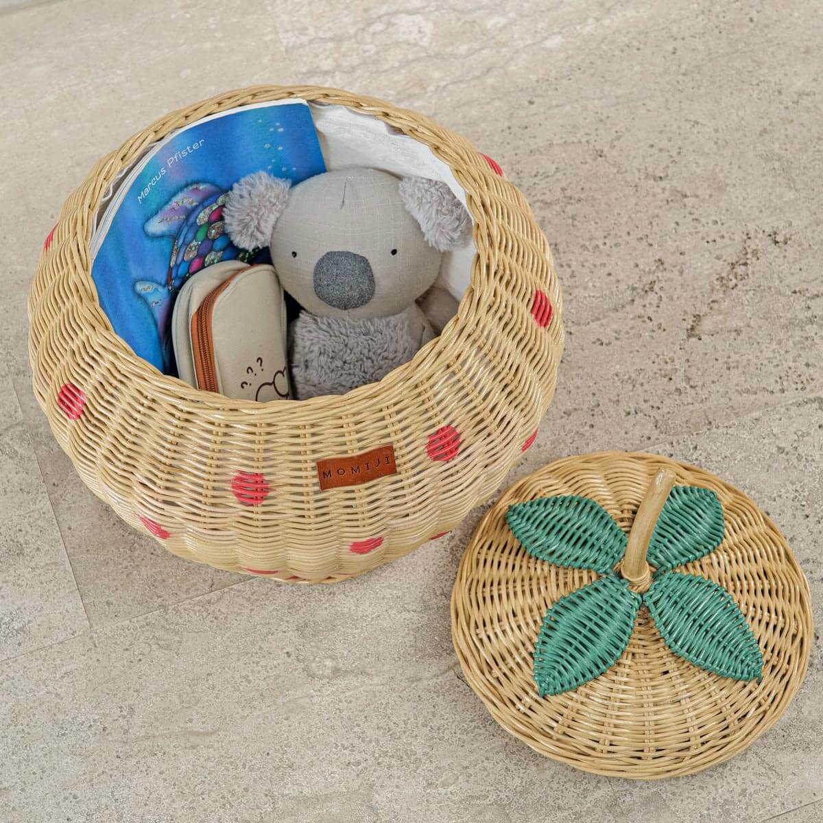 Top inside view of Strawberry Rattan Storage Basket with a book, stuffed toy and a pouch inside.