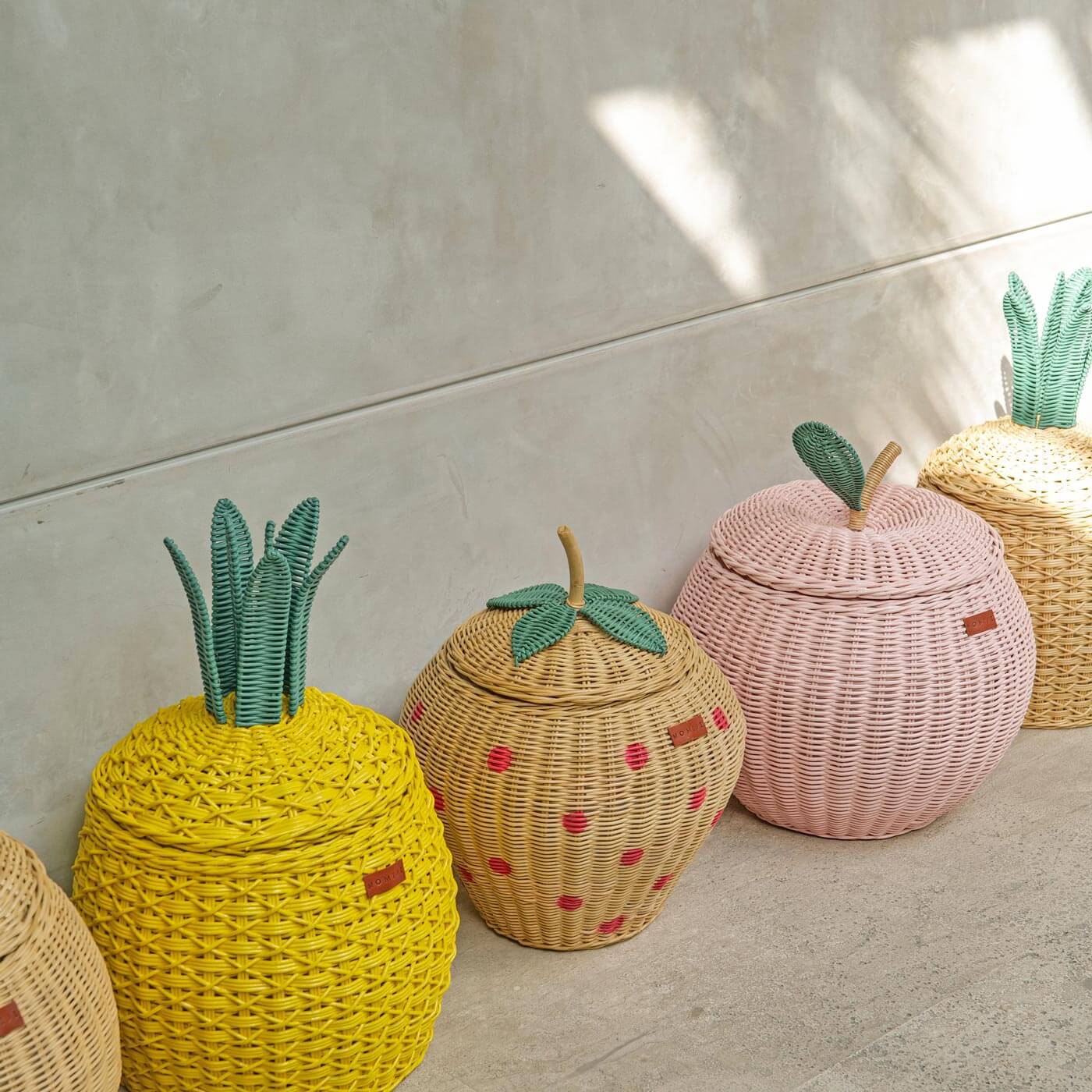 Strawberry Wicker Rattan Basket by MOMIJI displayed alongside apple and pineapple rattan baskets outdoors.