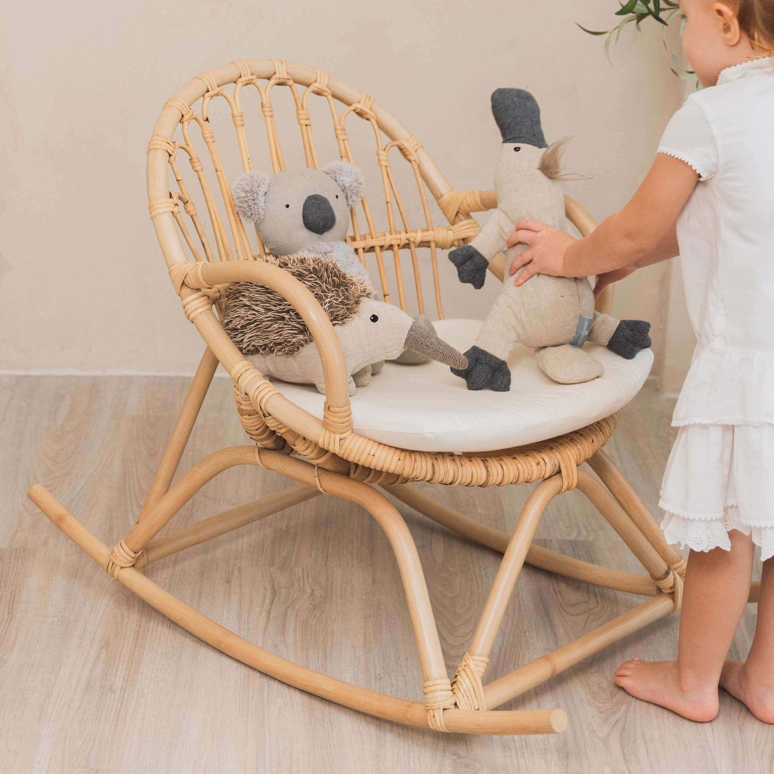 Child arranging dolls on the Twinkle Kids Rocking Chair by MOMIJI indoors.
