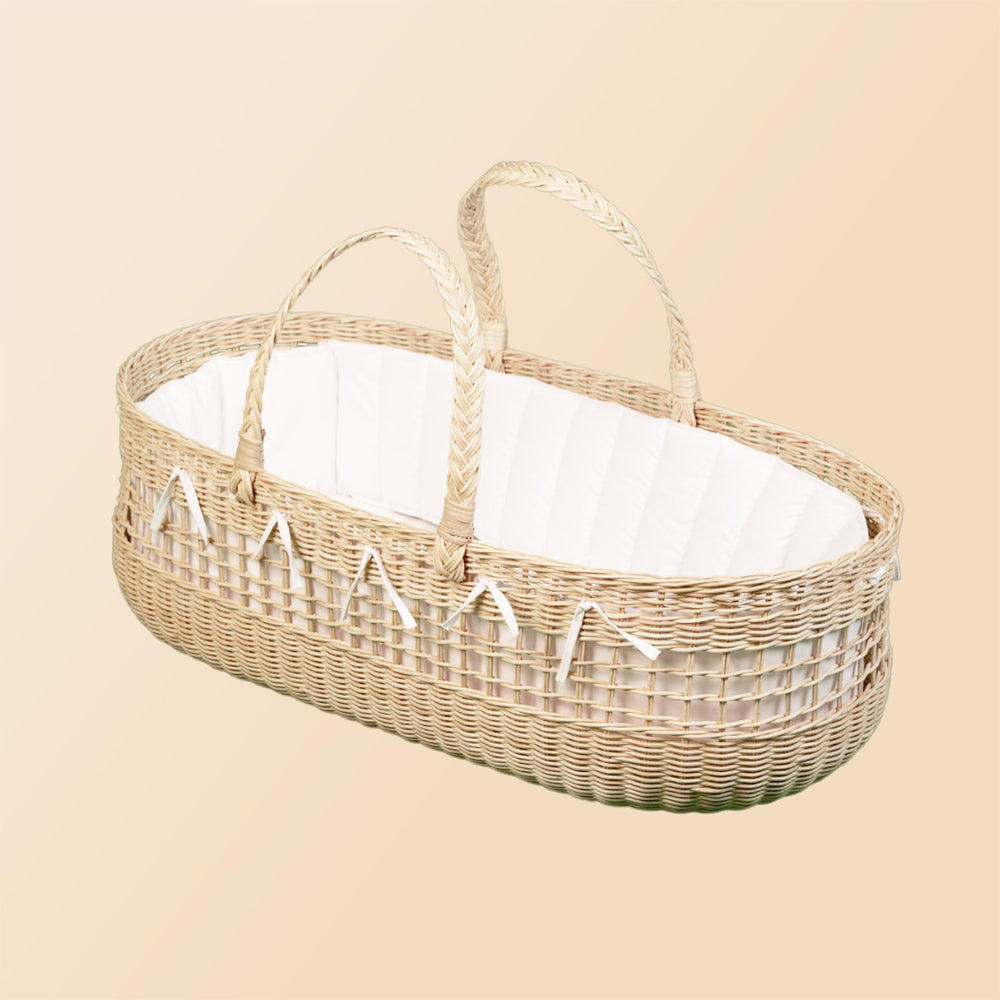 Angled view of the Vera Moses Rattan Basket by MOMIJI, showing the handwoven rattan structure and a white cushion inside.