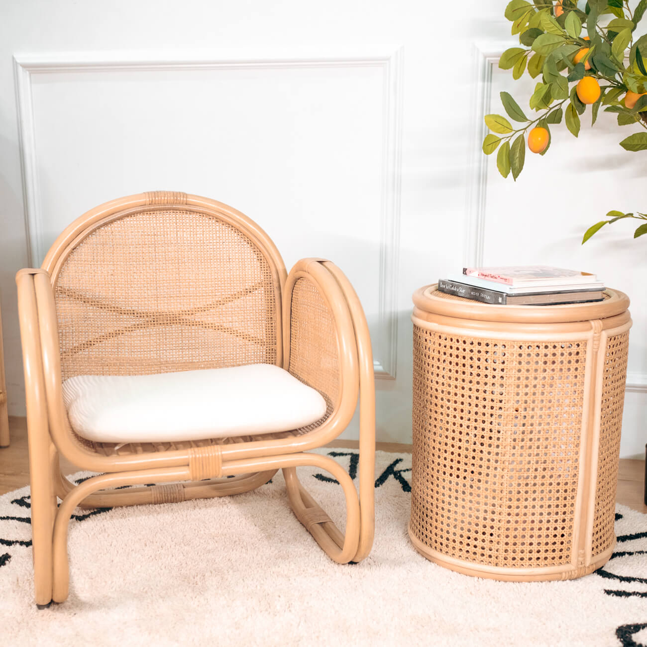 Child-sized rattan Willow Kids Lounge Chair by MOMIJI with a white cushion, placed in a room with a decorative plant.