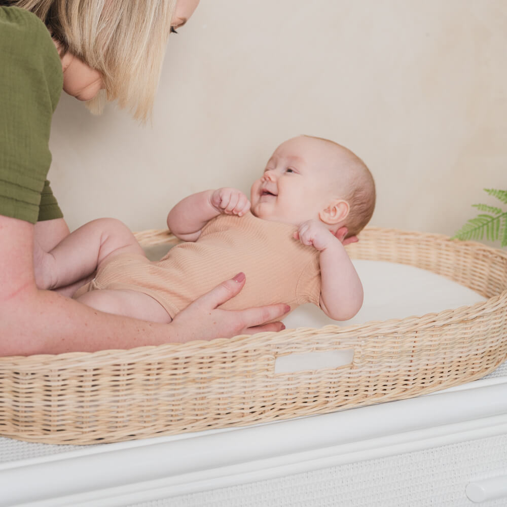 Baby resting inside the Xander Changing Basket by MOMIJI on a light-colored surface.