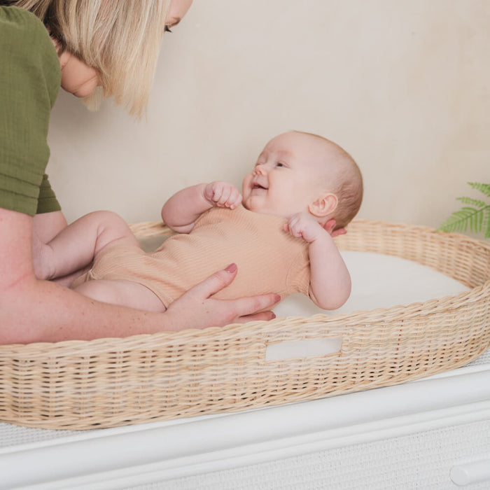 Baby resting inside the Xander Changing Basket by MOMIJI on a light-colored surface.