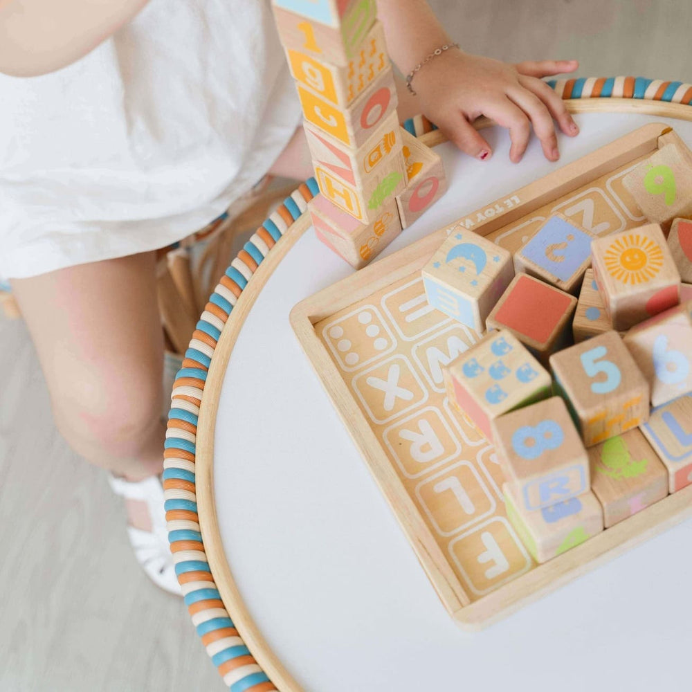 Child playing with wooden blocks featuring letters and numbers on a Xander Kids Table by MOMIJI.