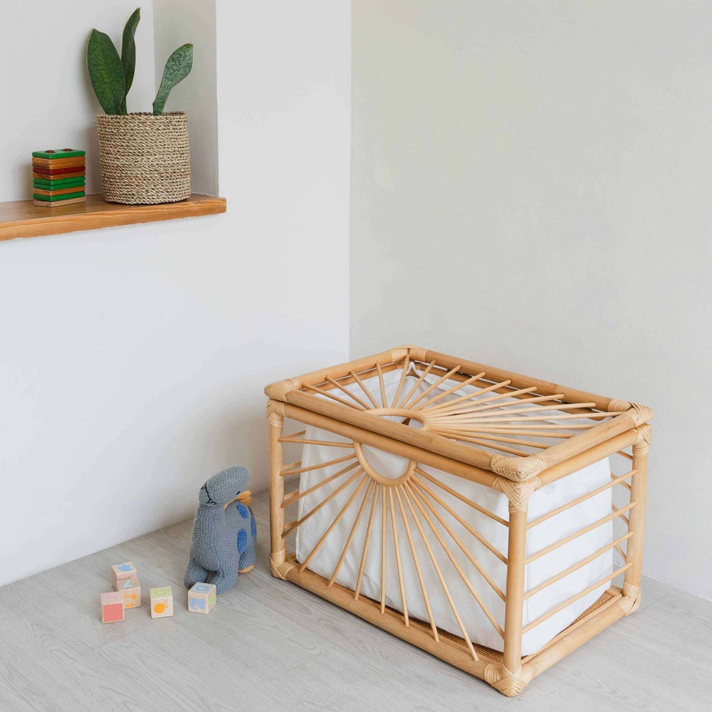 Wicker Xander Trunk by MOMIJI placed on a light wooden floor with toys and a plant in the background.