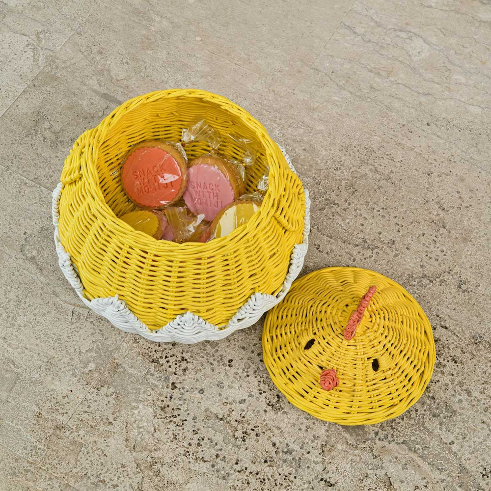 Handcrafted yellow rattan wicker chick basket shown with the lid off, filled with cookies and styled on a textured surface.