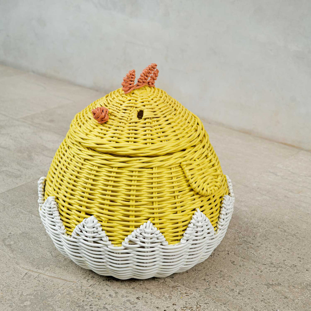 Tilted view of a handcrafted yellow rattan wicker chick storage basket by <+MOMIJI on a concrete floor, highlighting the wing design and sturdy structure.