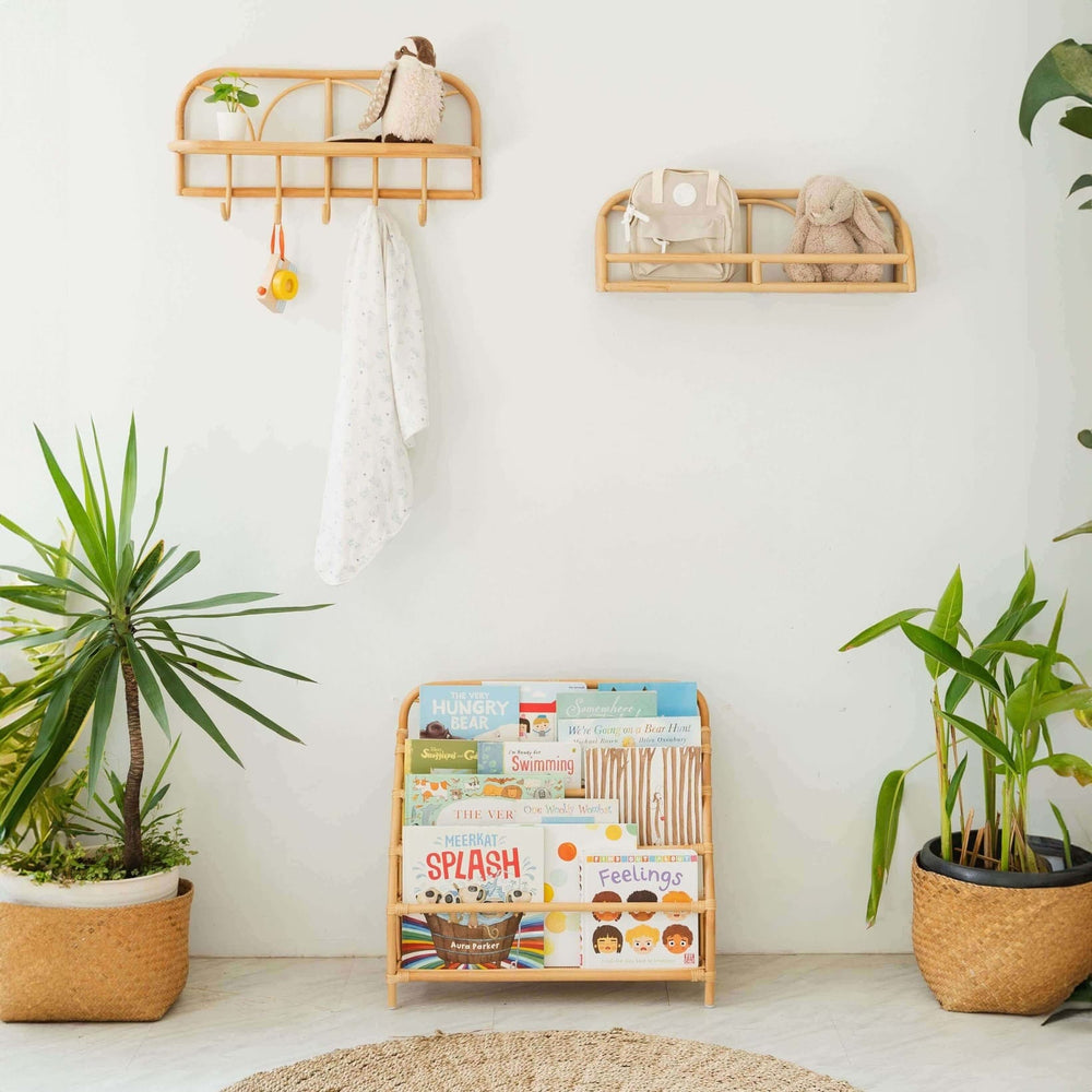 Elena Kids Montessori Bookshelf – Natural by MOMIJI with children's books in a room with plants and shelves on the wall.