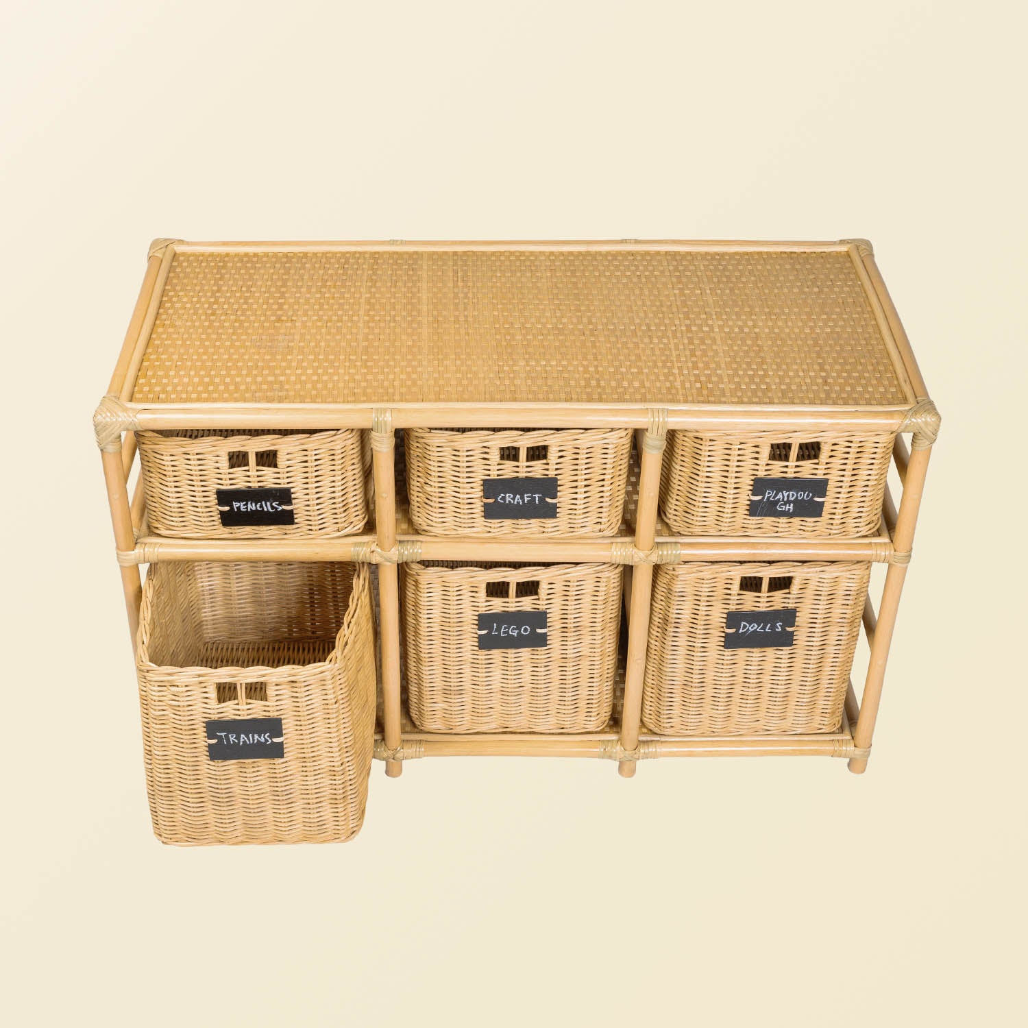 Front view of the Graha Montessori rattan storage shelf by MOMIJI with blackboard-labeled baskets in natural beige, featuring an open “Trains” basket.