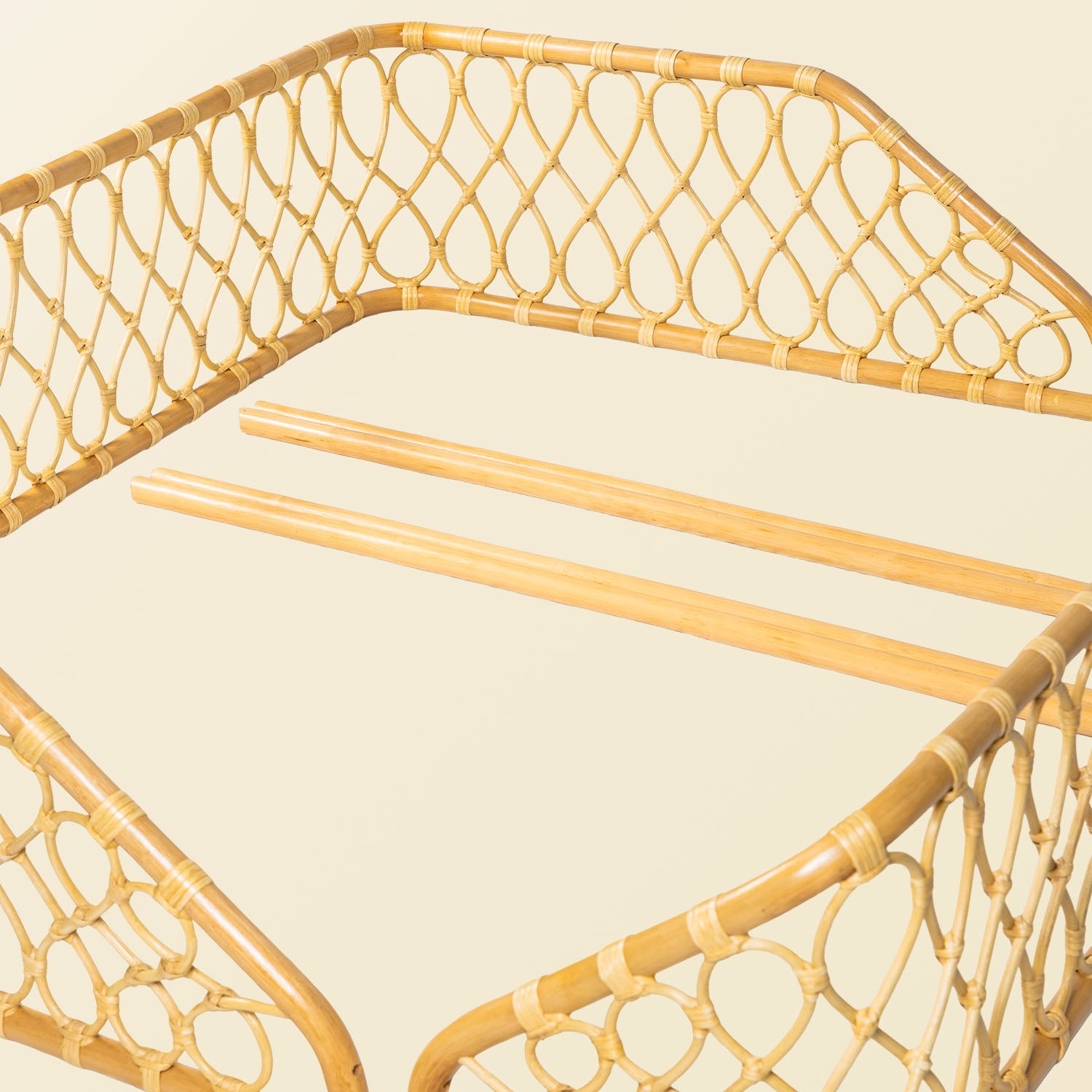 Close-up of the handcrafted rattan wicker Layla Montessori floor bed frame by MOMIJI in beige natural rattan with chopsticks, highlighting construction details.